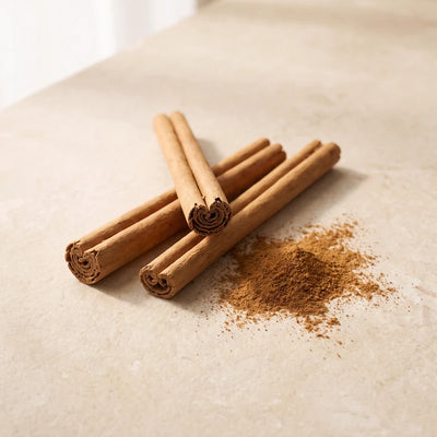 Ceylon cinnamon quills and cinnamon powder on warm stone.